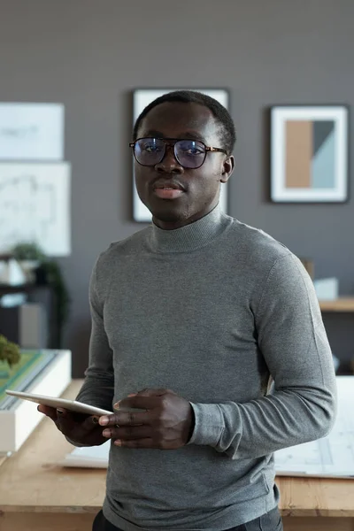 Jovem arquiteto masculino africano com tablet em pé contra o local de trabalho — Fotografia de Stock