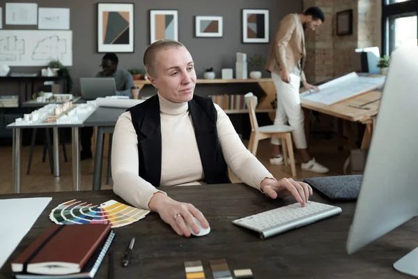 Diseñadora femenina madura mirando la pantalla de la computadora mientras trabaja por mesa —  Fotos de Stock