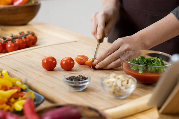 Hände junger Frauen hacken frische reife Kirschtomaten für den Salat — Stockfoto