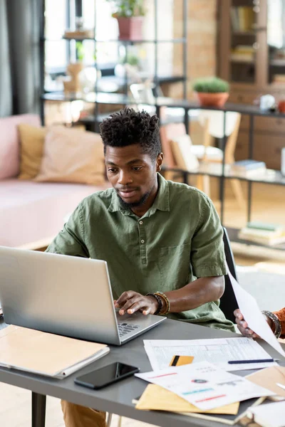 Young man of African ethnicity looking at laptop display while networking — 图库照片