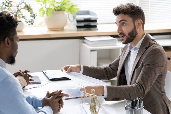 Young confident lawyer consulting African couple about mortgage