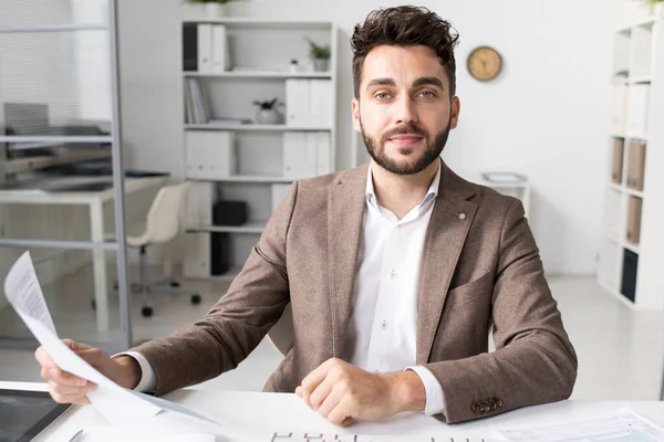 Contemporary young businessman with paper sitting by workplace — Fotografia de Stock