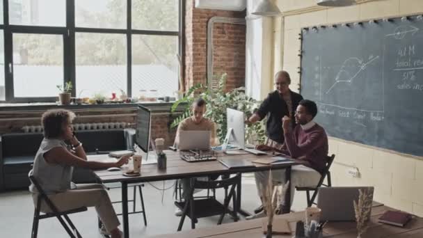 四个多种族同事在电脑上长时间工作 白天坐在阁楼式的协同工作空间的桌旁 为项目工作 — 图库视频影像