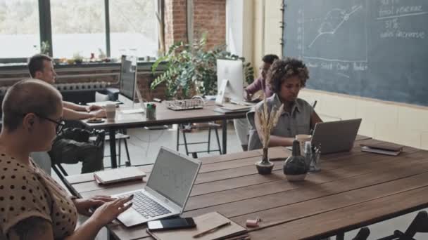 白天用电脑在不同的人中间追踪坐在同事位置上的年轻黑人妇女 — 图库视频影像