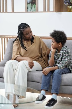 Küçük oğlunun elini omzunda tutan genç bir kadın.
