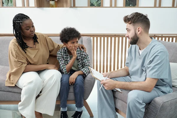 Contemporary dentist with clipboard consulting little boy with toothache — Stock Photo, Image