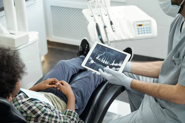 Gloved hands of stomatologist with tablet displaying x-ray of human teeth — Stock Photo, Image