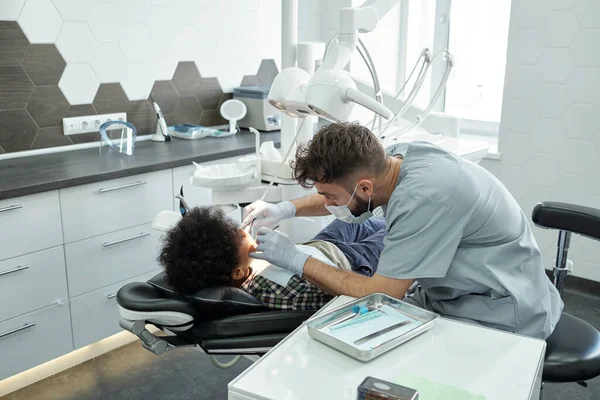 Dentista contemporâneo curvando-se sobre o pequeno paciente — Fotografia de Stock