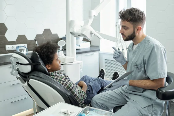 Young confident dentist with tablet consulting little patient — Stock Photo, Image