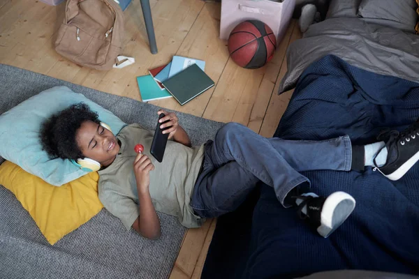 Gelukkig kleine jongen in hoofdtelefoon met lolly en kijken naar online video — Stockfoto