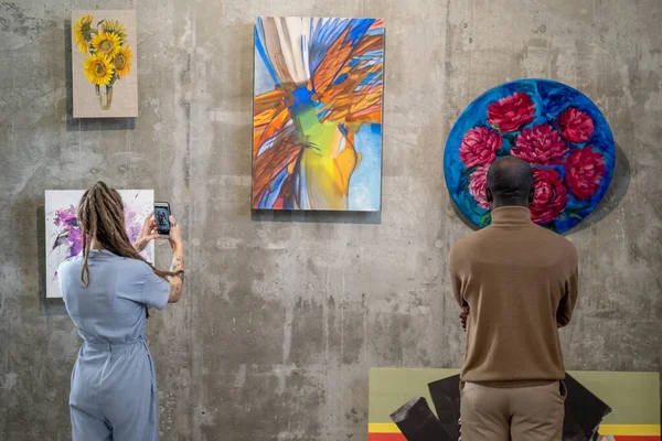 Back view of two intercultural visitors of modern art gallery — Stock Photo, Image