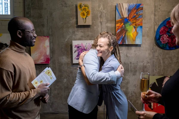 Felice giovane donna abbracciando artista moderno in galleria — Foto Stock