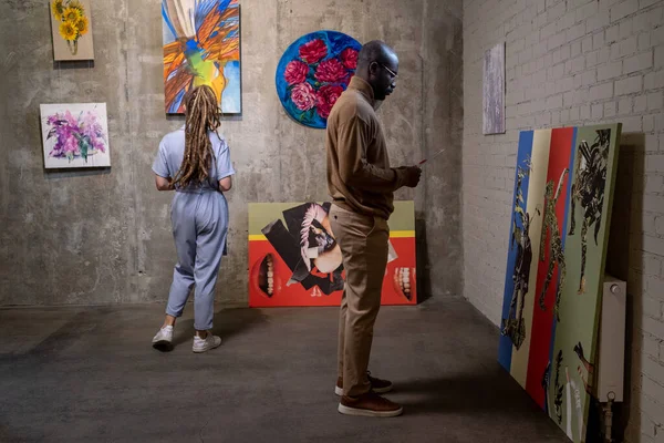 Jovem africano com folheto em pé na frente de obras de arte — Fotografia de Stock
