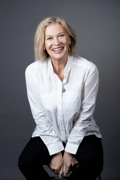 Happy mature woman posing on the chair — Stock Photo, Image