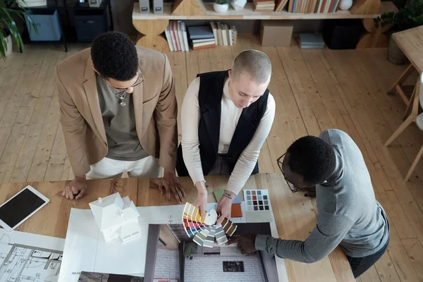 Dos diseñadores de interiores que muestran la paleta de colores al cliente masculino africano — Foto de Stock