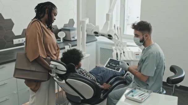 Orta Uzunluktaki Beyaz Erkek Doktor Dişçi Koltuğunda Oturan Yaşındaki Çocuğa — Stok video