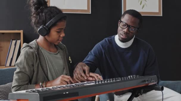 Medium Nastolatki Słuchawkach Uczy Się Grać Syntezatora Młodym Czarnym Nauczycielem — Wideo stockowe