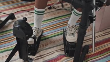 Bacakları tanınmayan, spor ayakkabı giyen ve yüksek çoraplar giyen bas davul pedalı kullanarak elektronik davul çalan bir öğrenci.