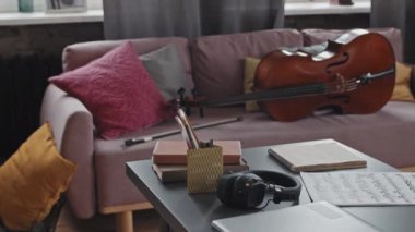 Gündüz vakti, üzerinde notlar, kulaklıklar ve kitaplar olan pembe kanepenin önünde otururken,