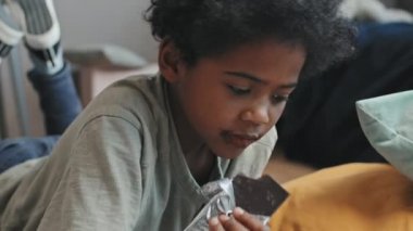 Gündüz vakti 10 yaşındaki zenci bir çocuğun karnının üstüne yatıp çikolata çizip yemesi.