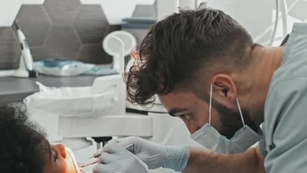 병원의 의자에 소년의 도구를 사용하고 치료를 시작하는 마스크와 장갑을 의사를 — 비디오
