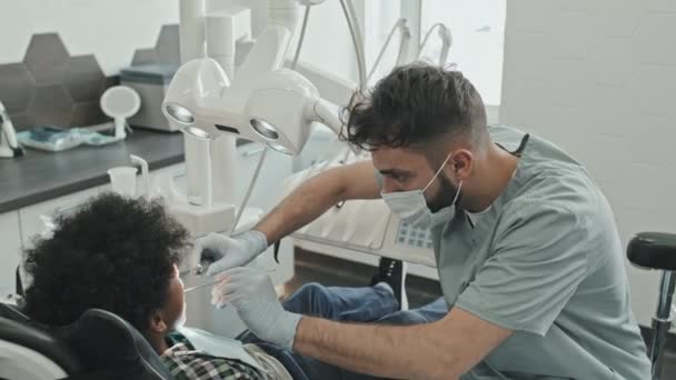 코카서스 의사의 마스크 수술복을 사무실에서 의자에 소년을 — 비디오
