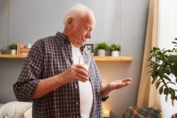 Старший чоловік приймає ліки вдома — стокове фото