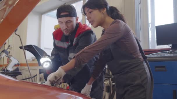 Beyaz Tenli Erkek Tamirci Spanyol Bayan Meslektaşıyla Araba Tamirhanesinde Çalışırken — Stok video