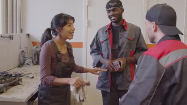 多种族的男女技工一起站在汽车修理店里 在工作日里微笑着聊天 — 图库视频影像