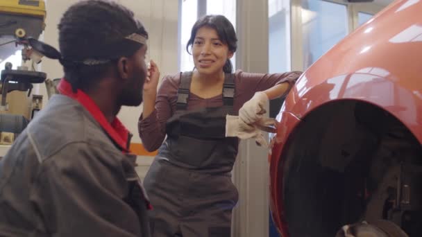 Mecânico Feminino Hispânico Inclinado Carro Sem Pneu Falando Com Colega — Vídeo de Stock