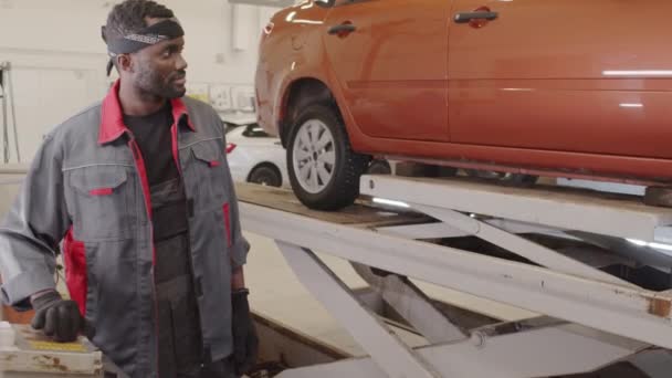 Africano Americano Mecânico Abaixando Elevador Carro Enquanto Trabalhava Oficina Reparação — Vídeo de Stock