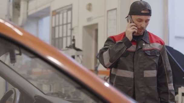 Mecánico Masculino Uniforme Pie Taller Reparación Automóviles Hablando Por Teléfono — Vídeos de Stock