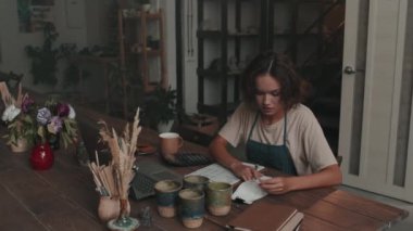 Önlük giyen, çömlekçilik atölyesinde masada oturan, gündüzleri kayıt tutan beyaz bir kadının sandığı.