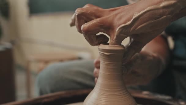 陶器の車輪の上に柔らかい粘土の認識できないセラミスト座って形の花瓶の手のクローズアップ ボトルネックを作る — ストック動画