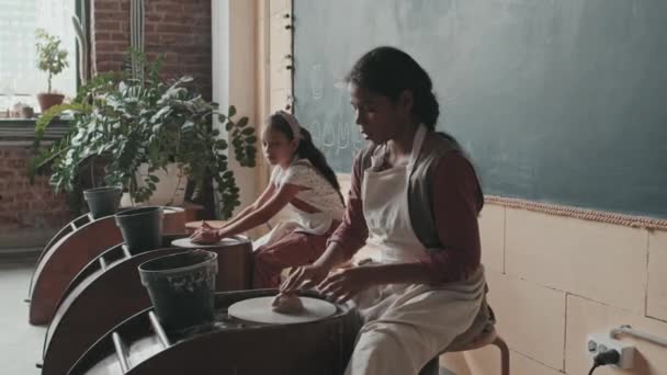 Opsluiting Van Zwarte Blanke Meisjes Die Overdag Aan Pottenbakkerswielen Zitten — Stockvideo