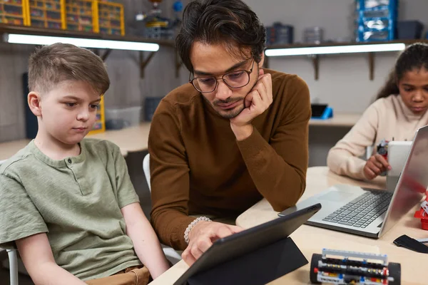 Ung man hjälper barn i robotteknik klass — Stockfoto
