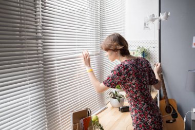 Venedik panjurlarından bakan hasta genç bir kadın.