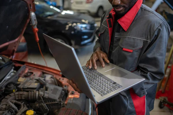 Part of repairman in workwear holding laptop while consulting clients online — Stock Photo, Image