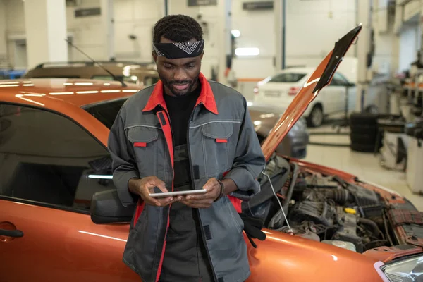 Young African man in workwear looking at tablet screen — Stock Photo, Image