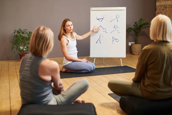 Junge Fitnesstrainerin präsentiert eine Reihe von Übungen auf Whiteboard — Stockfoto