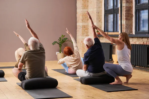 Junge Fitnesstrainerin hilft Senioren bei Bewegung — Stockfoto