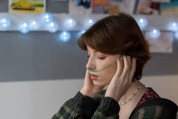 Sick teenage girl with oxygen nose pipe touching temples — Stock Photo, Image