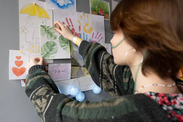 Paziente femminile adolescente di ospedale che appende il disegno di foglie verdi su parete — Foto Stock