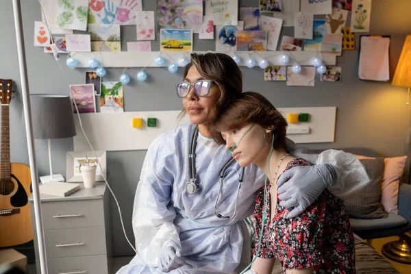 Verpleegster in werkkleding en bril omhelzing tiener patiënt — Stockfoto