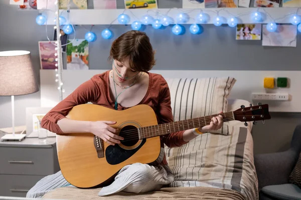Teenage dívka hraje na kytaru, zatímco sedí na posteli v nemocnici oddělení — Stock fotografie