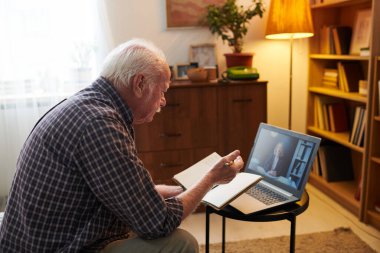 Yaşlı adam bilgisayarda online danışmanlık yapıyor.