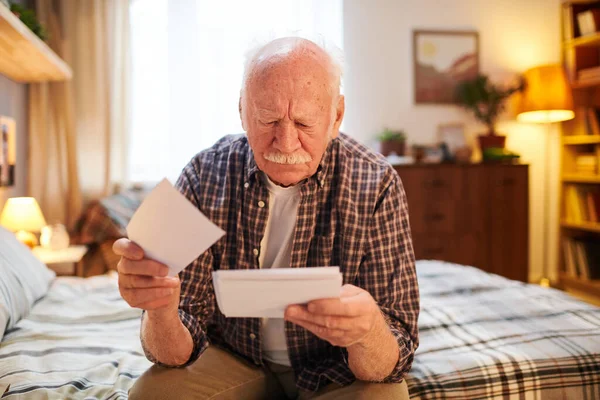 Vieil homme se souvenant des événements passés avec des photos — Photo