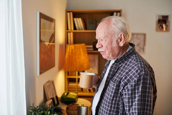 У віці чоловік п'є чай вдома — стокове фото