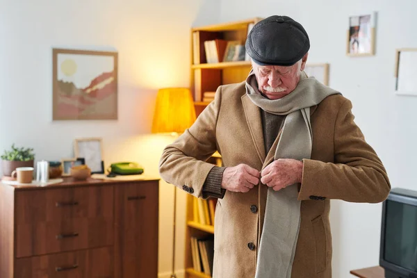 Hombre mayor poniéndose un abrigo para dar un paseo — Foto de Stock