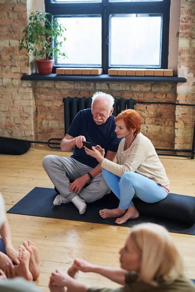 Seniorenpaar benutzt Telefon im Fitnessstudio — Stockfoto